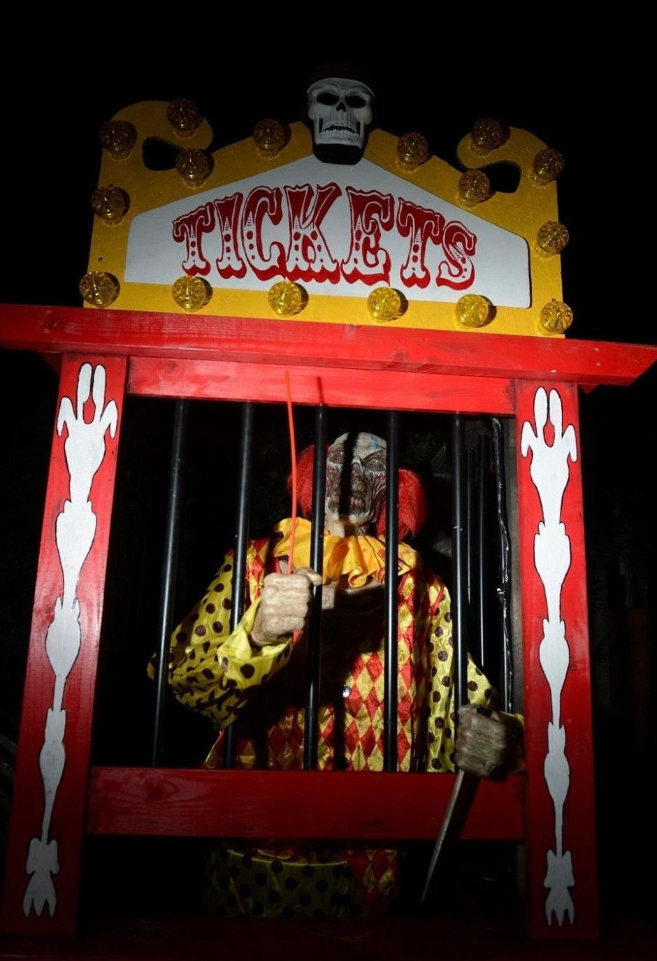 Ticket booth with a clown mannequin in a colorful costume holding bars.